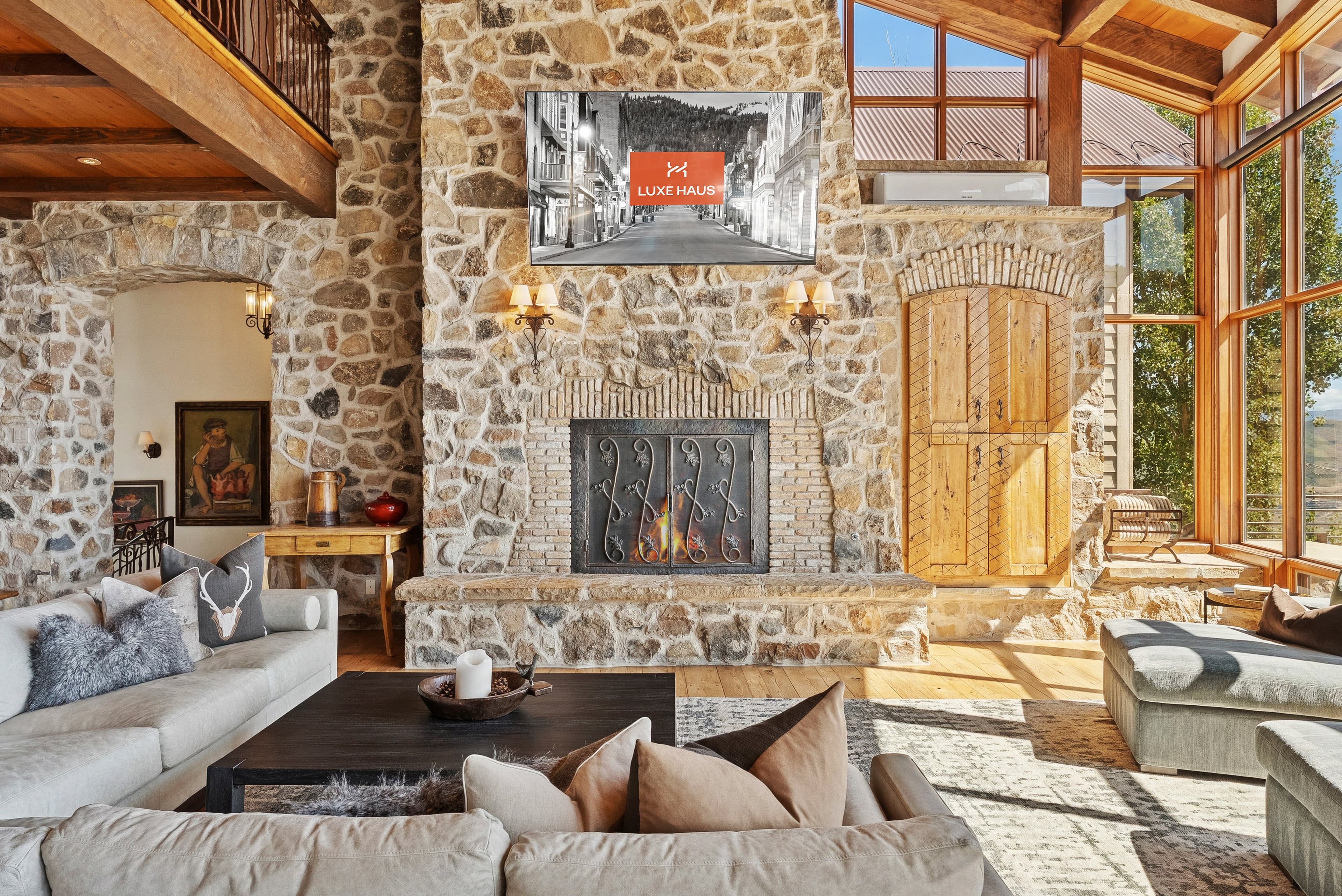 Bright living room with stone fireplace, large windows, and sectional sofa.