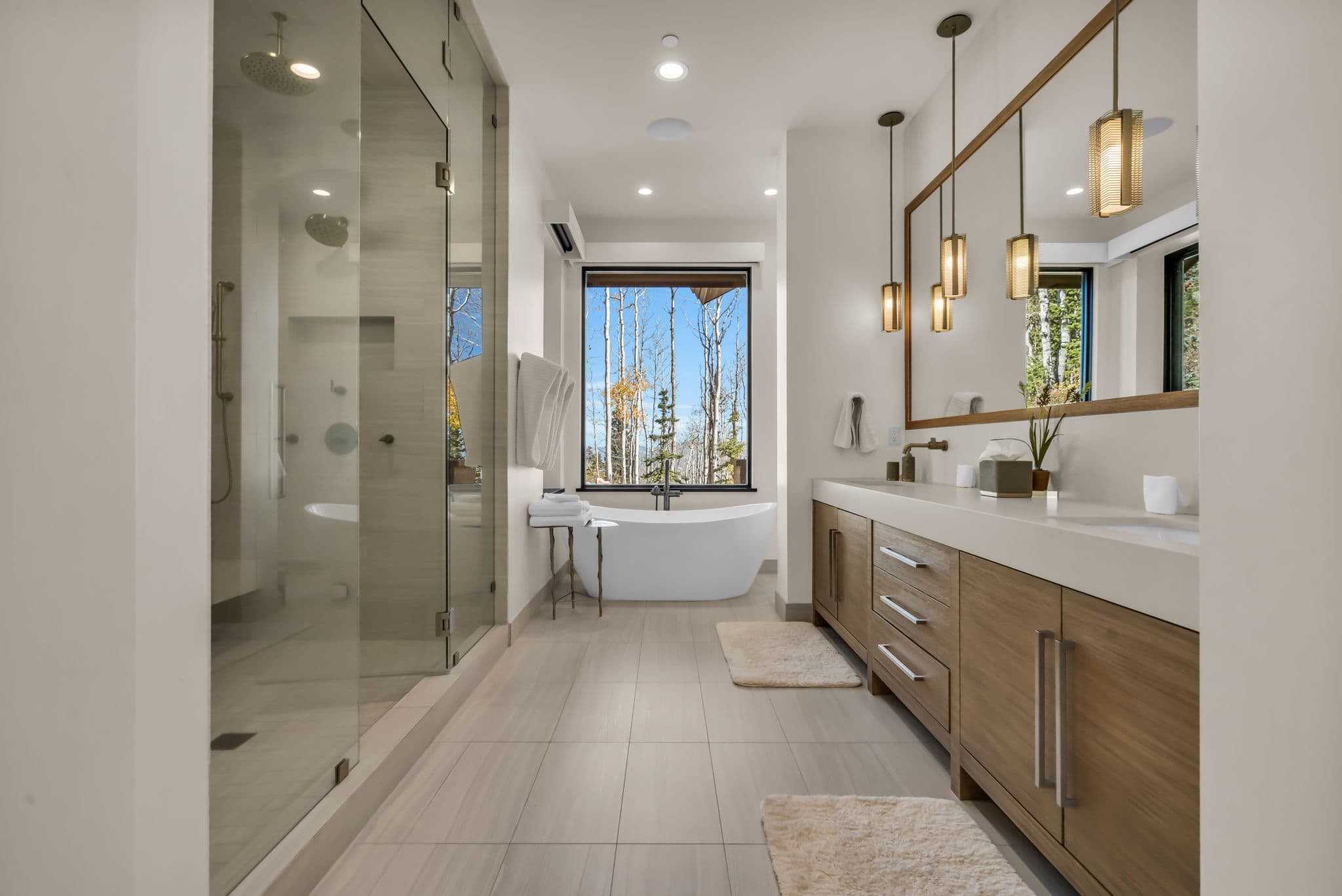 Double Sink Bathroom with a Freestanding Bathtub, Mirror, and Pending Lamps