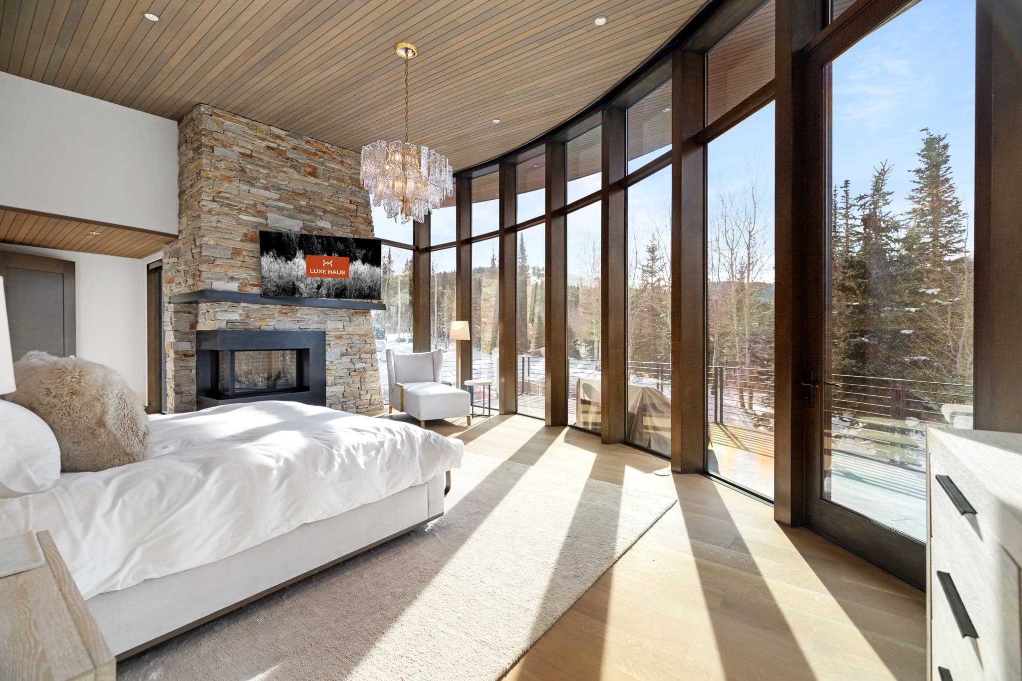 A bedroom with a bed, a fireplace, and a flatscreen tv.