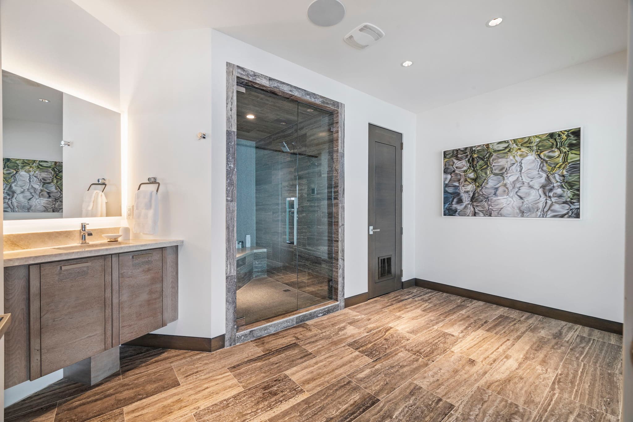 A bathroom with a shower, a sink, and wood flooring.