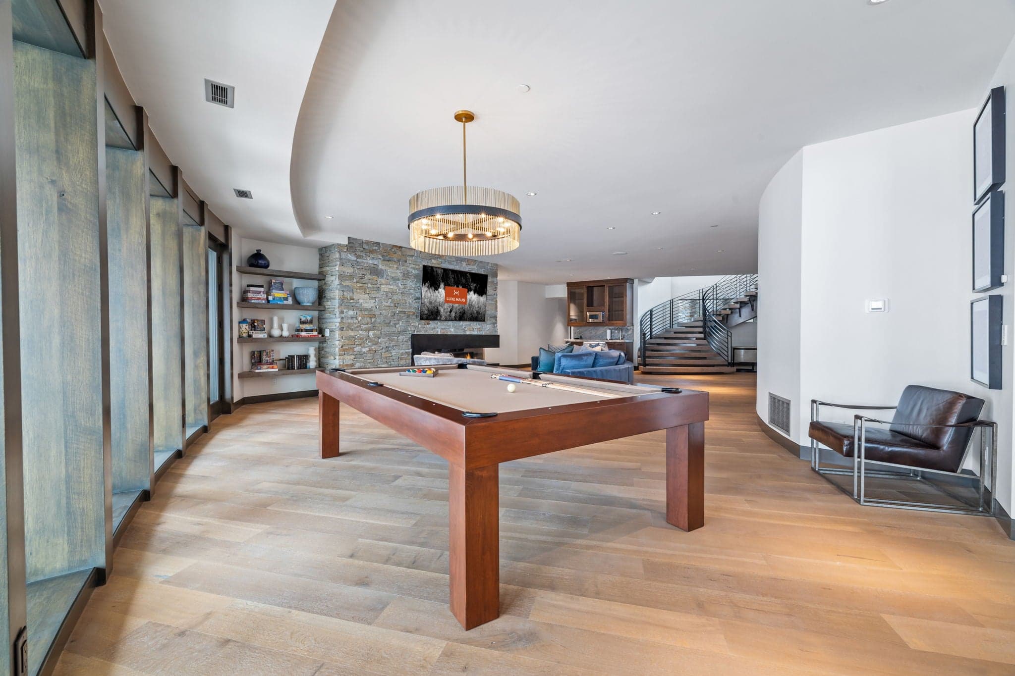 A room with a wood pool table and seating area.