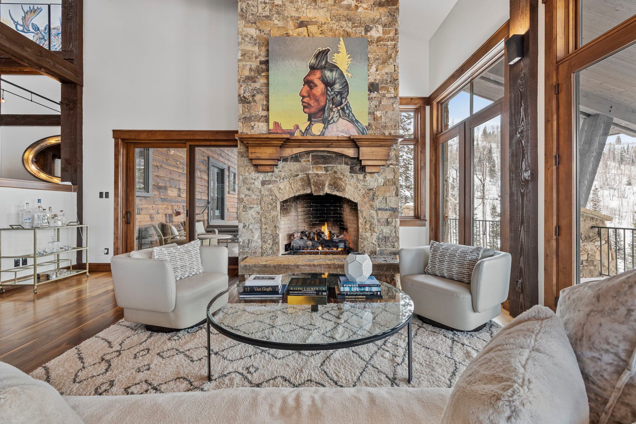 a view of a luxury living room from the couch. the fireplace is two stories tall and there is a large piece of art mounted on the mantel with a native american