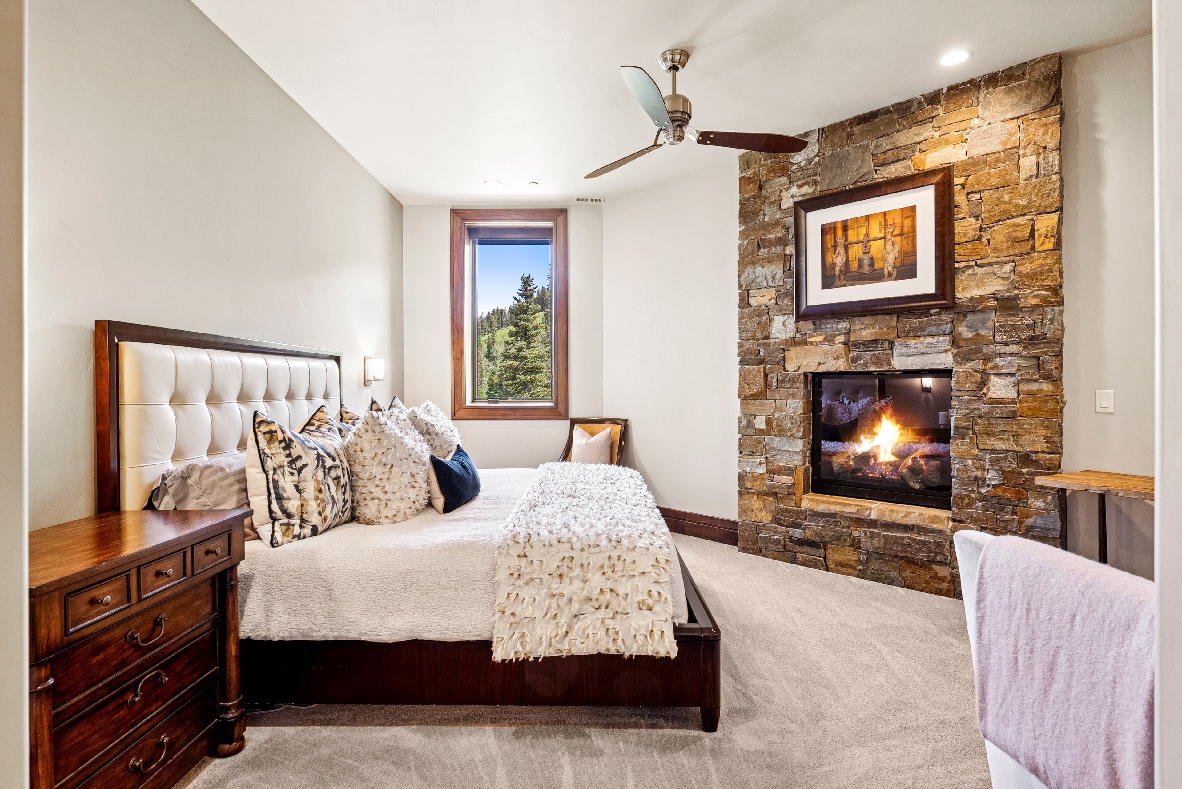guest suite with view of fireplace with warm fire glowing and large painting above fireplace